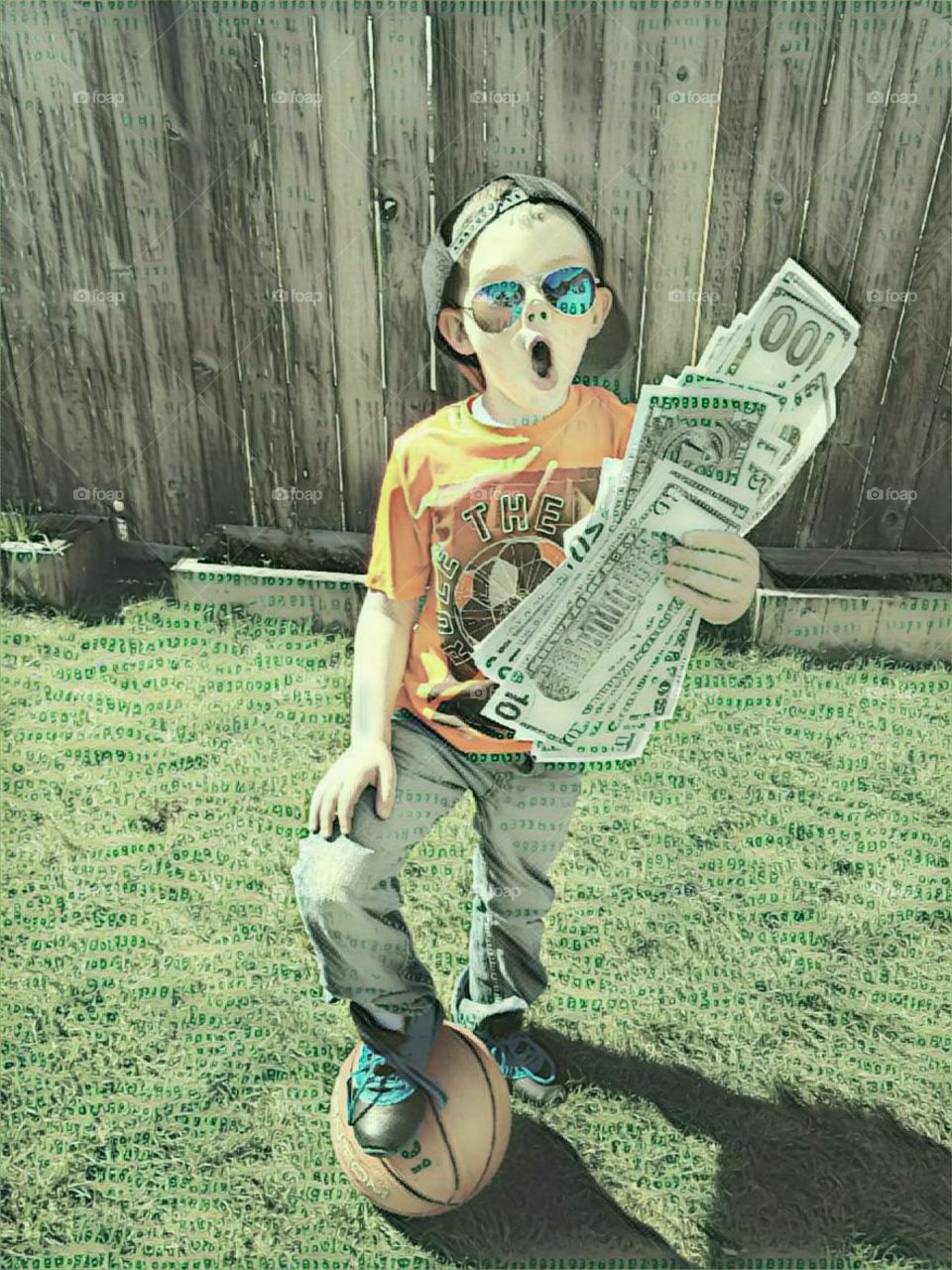 Abstract photo of boy on green lawn, holding oversized money with surprised look on his face.