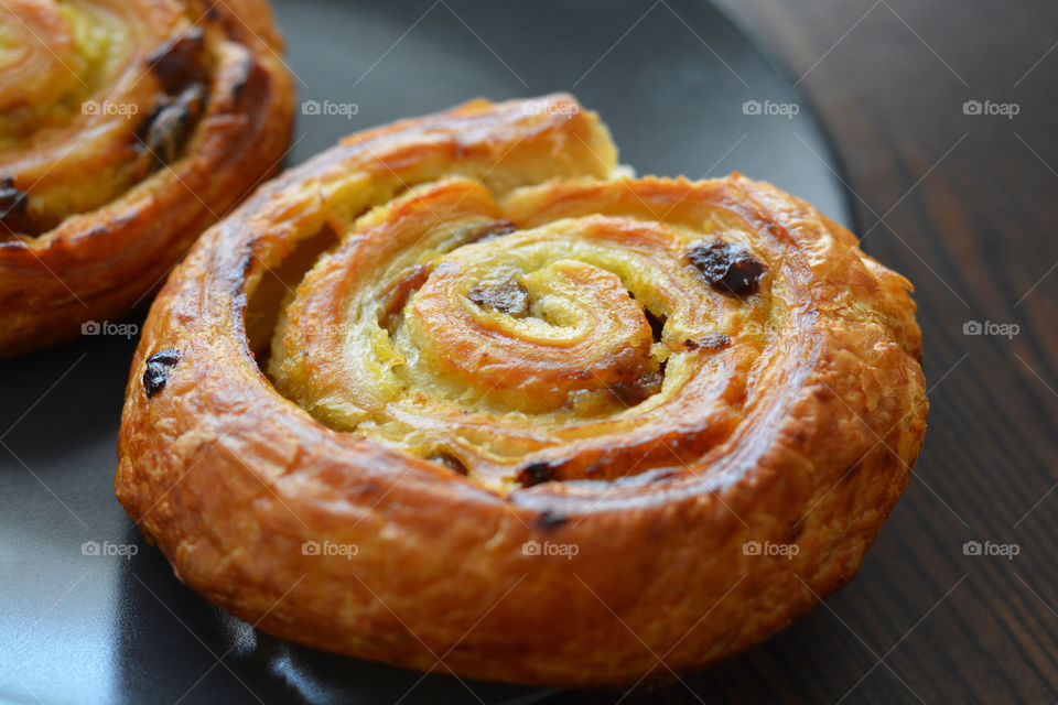 Danish raisin swirls on a black plate.