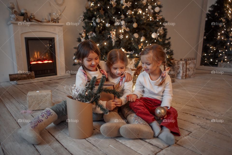 Little sisters near Christmas tree at home