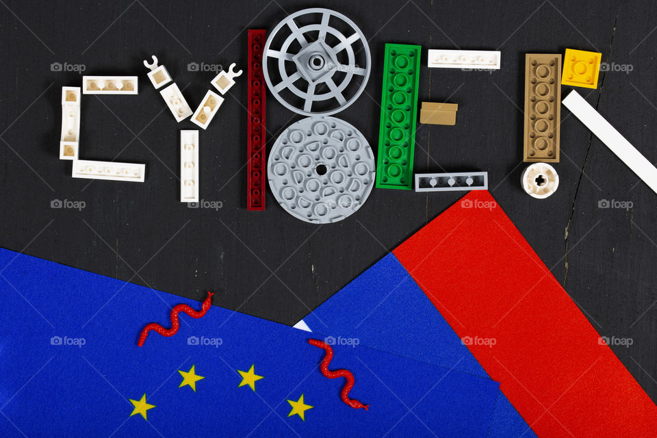 The word CYBER composed of pieces of LEGO and flags of EU and Russia. Flat lay
