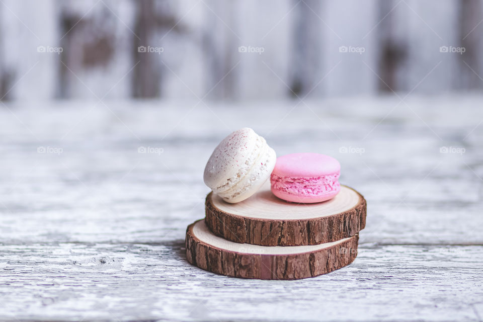 Macarons with cream at the wooden table on the blurry background.