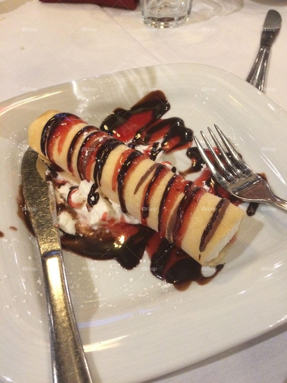 Crepe stuffed with vanilla ice cream drizzled with chocolate and strawberry sauce. A dessert lovers dream. 