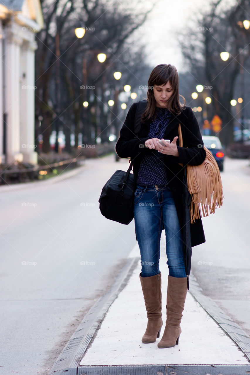 Woman on street holding mobile phone in hand