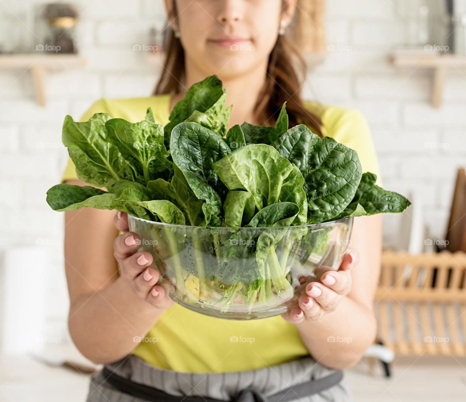 woman holding spinach bowl