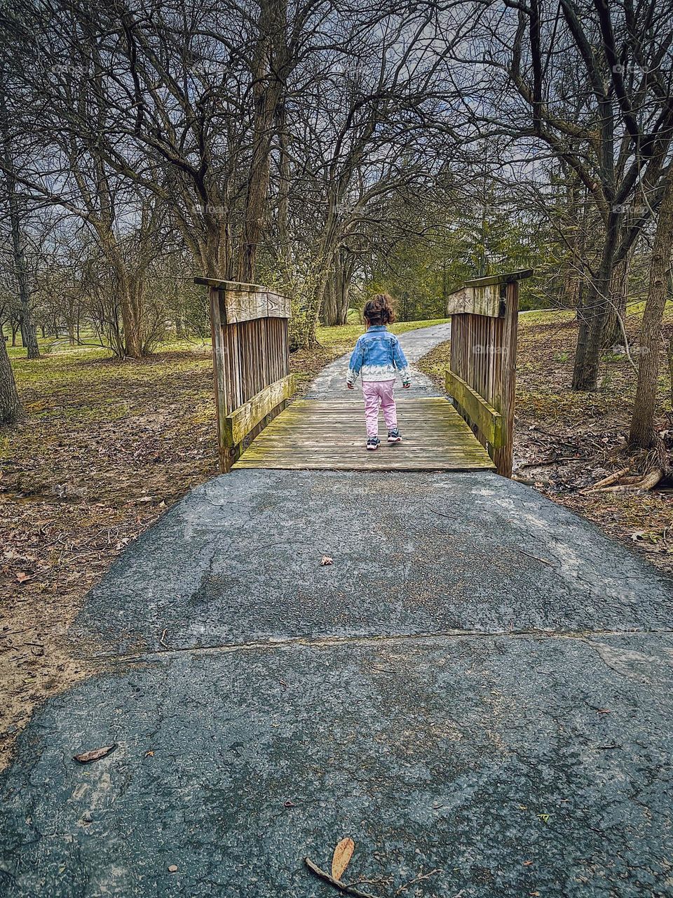 Toddler girl walks across bridge in the park, springtime in the park with kids, fun with family in nature, enjoying nature together, family lifestyle outdoors, child walks across bridge, take me to the other side 