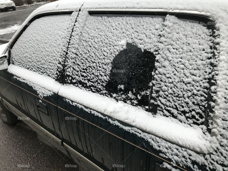 Car under snow, frozen window, winter weather.