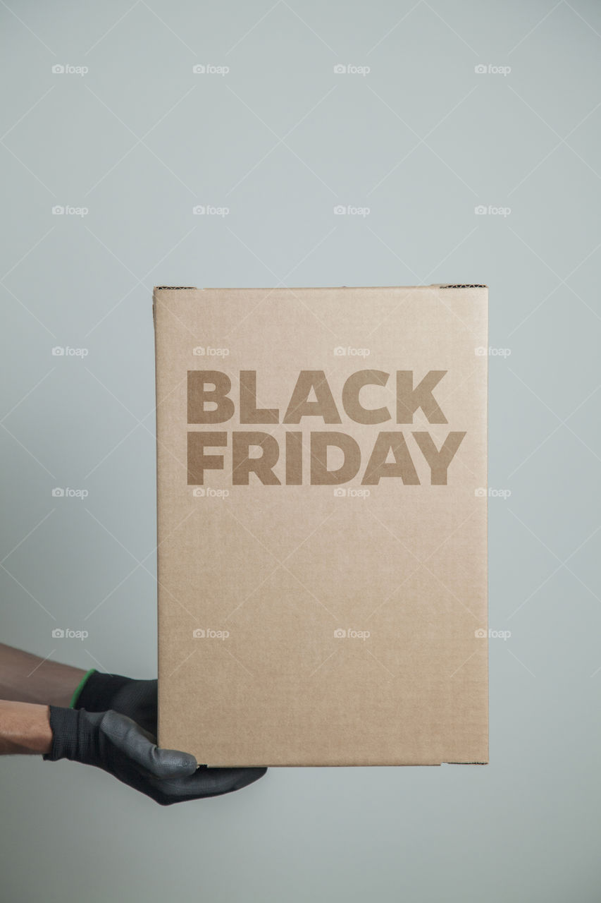 Cardboard box with black friday order written on the box placed on the floor in an empty room with a neutral background. delivery concept. economy concept. black friday concept. shopping concept.