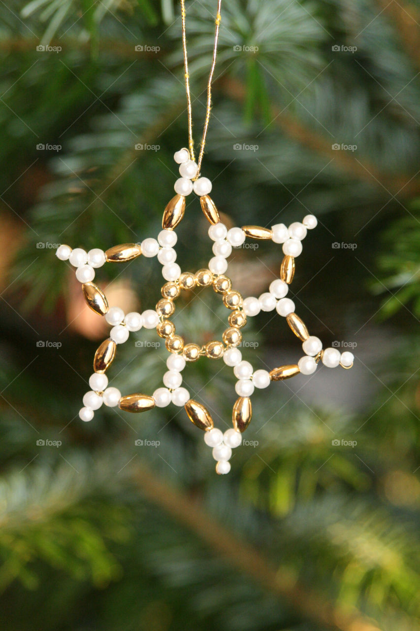 golden star made of pearls hanging on a christmas tree