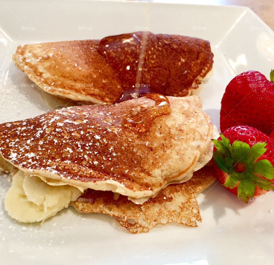 Fresh bananas stuffed pancakes & fresh strawberries drizzled with maple syrup 
