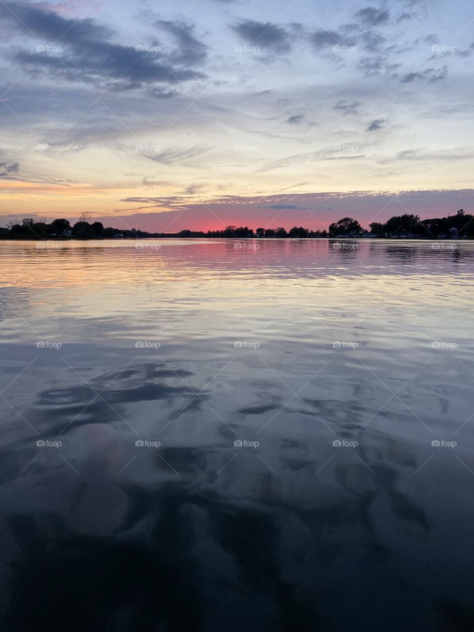 Warm colors in a cloudy sky makes a beautiful sunset reflection over a calm lake. 