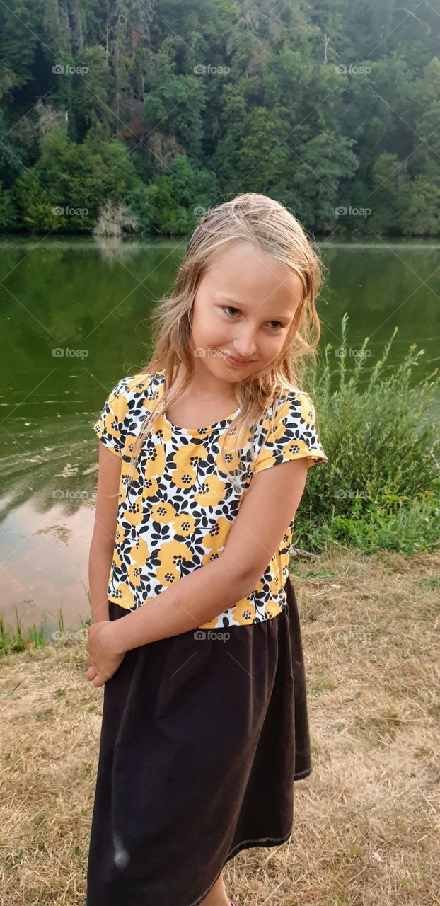 Little girl standing by lake in summer