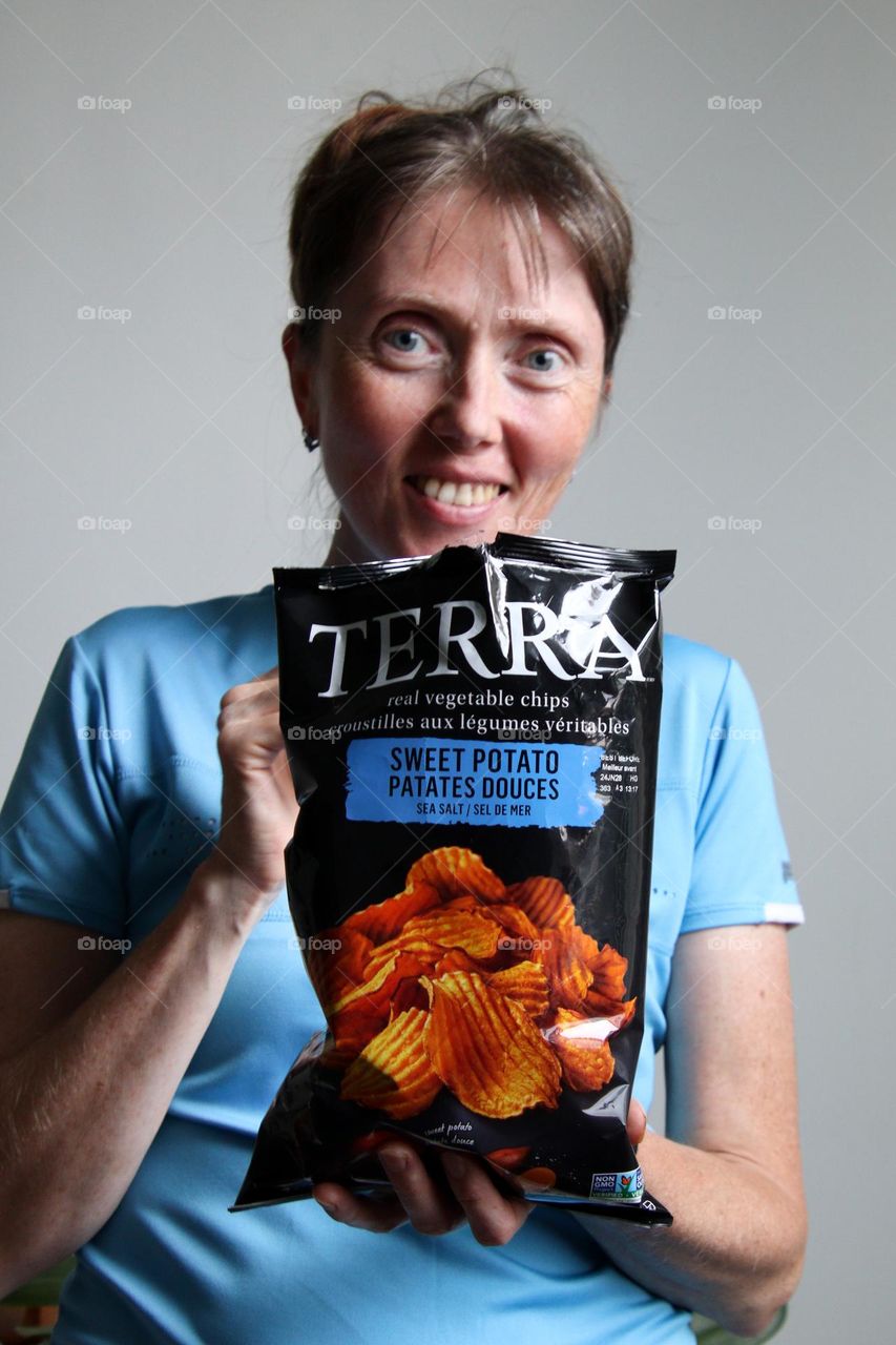 Happy middle-aged Caucasian woman with a bag of chips