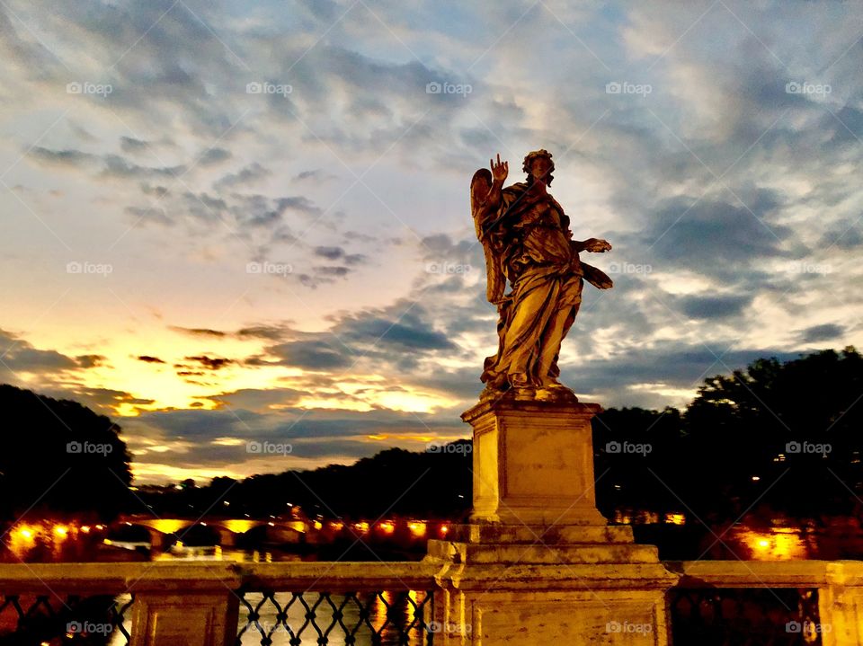 Statue on bridge in Rome, Italy during a cloudy early morning sunrise