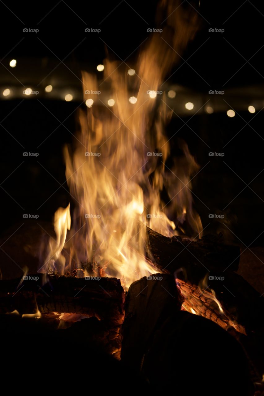 Fire with a smile; Large backyard fire with hanging lights in the background.