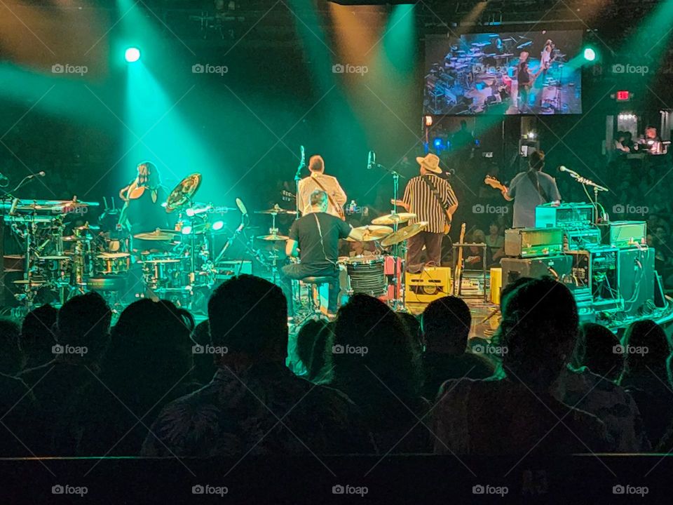 A rock band plays on a rotating stage and is seen from behind