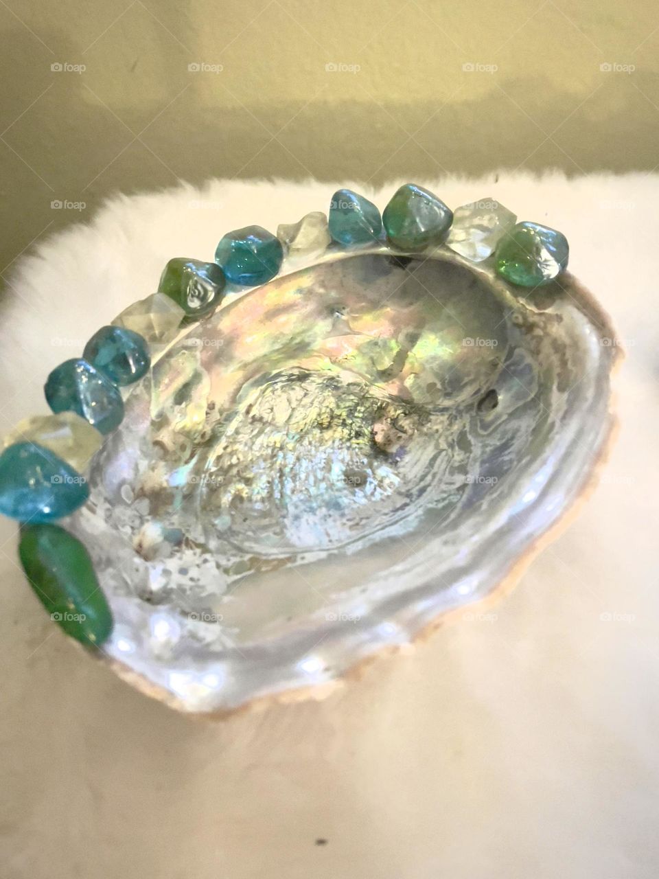 A abalone shell with multi colored beads on the edge to make a soap dish.