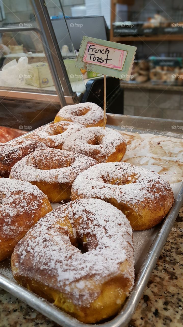 French Toast Bagels at a New Jersey Delicatessen Bakery. Powder sugar and cinnamon dusted across fresh baked goods on their baking sheet.