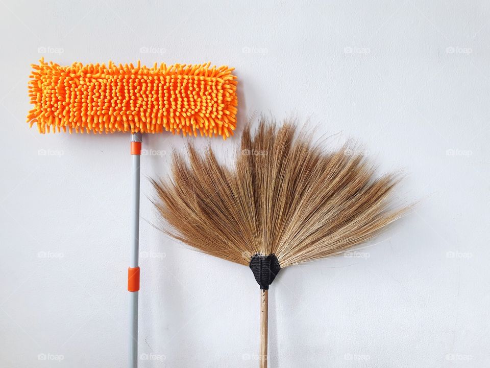 orange mop and broom with white wall
