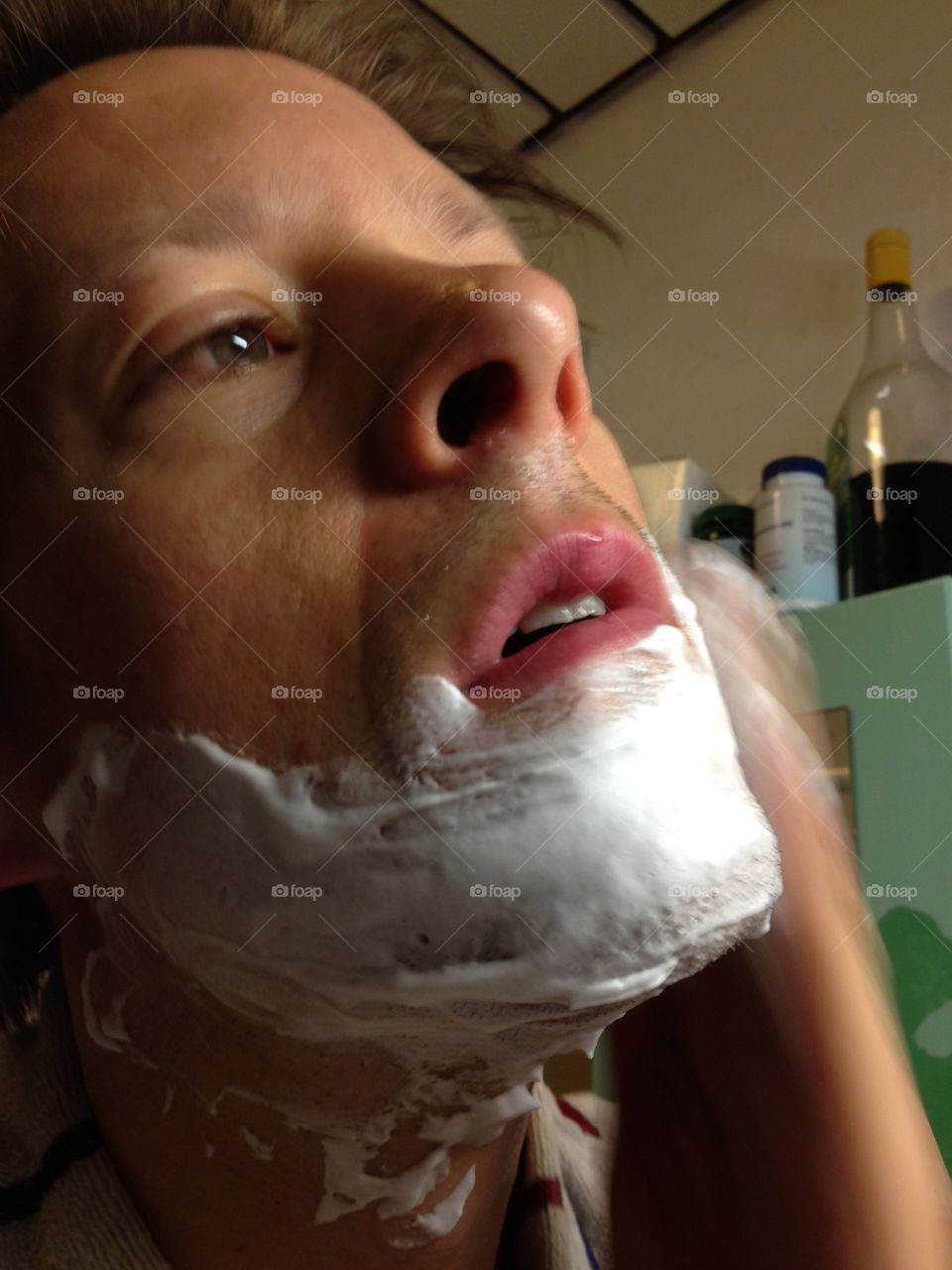 Man looking focused and applying shaving foam in the bathroom.