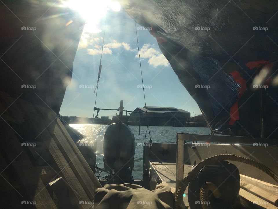 The early morning sun comes in underneath the tarp on the front deck of Salvation, our sailboat in Newtown Creek, Long Island City, Queens, New York casting reflections all around. Photo from 2018. Hypnotic Productions