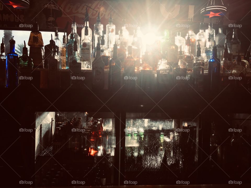 Sunshine shining through liquor bottles at the bar