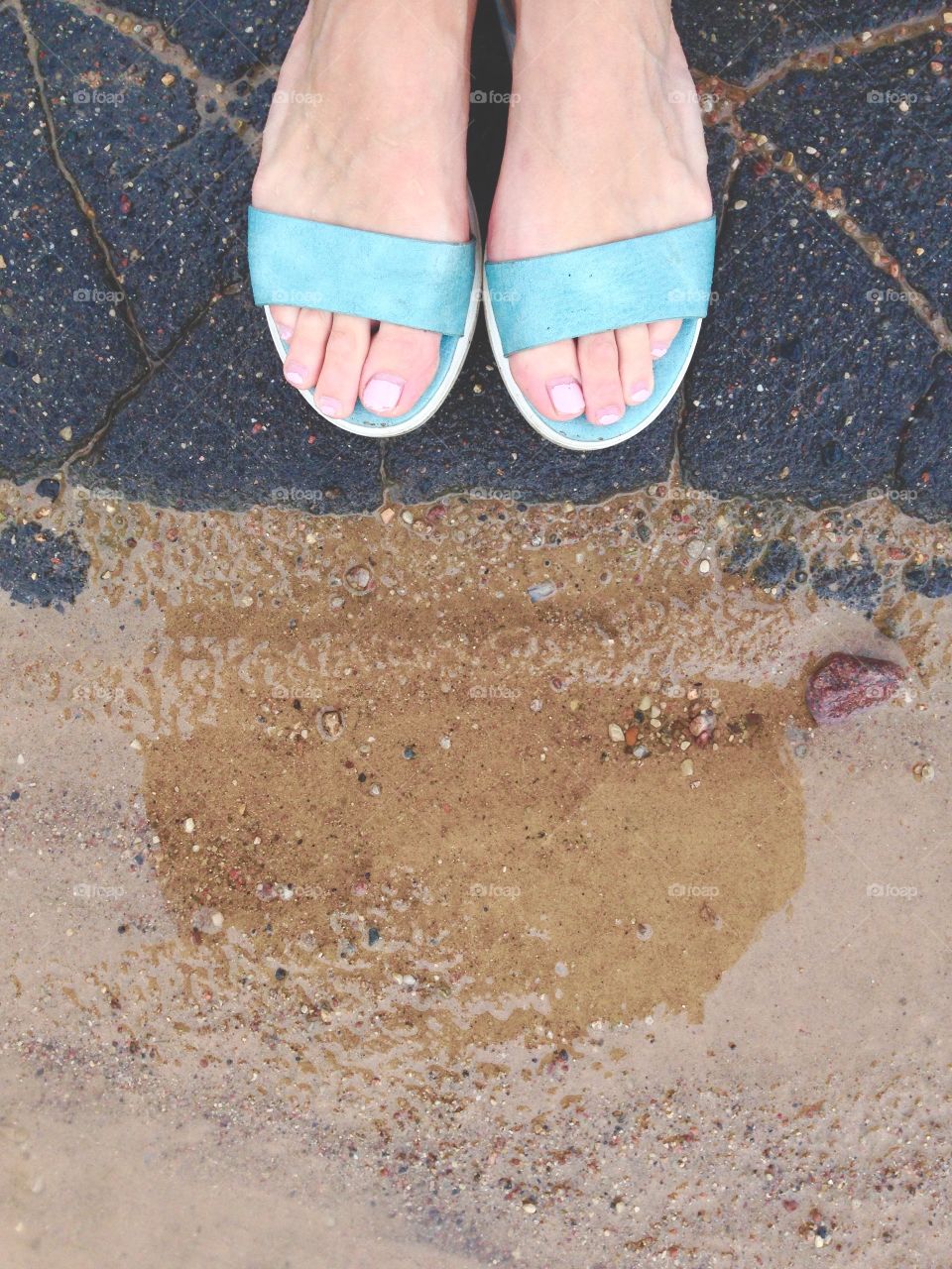 Feet in green sandals in front of road and sand in same time