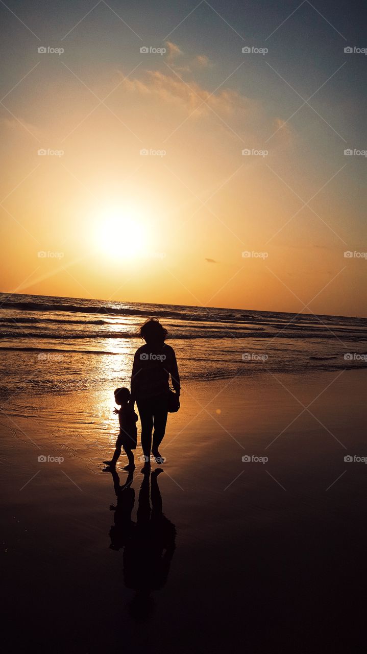 Little baby enjoying sunset with Mother in beach Nature
