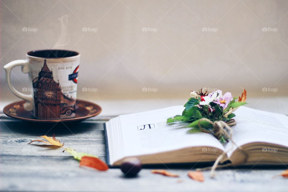 Open book and a cup of tea with fall flowers 