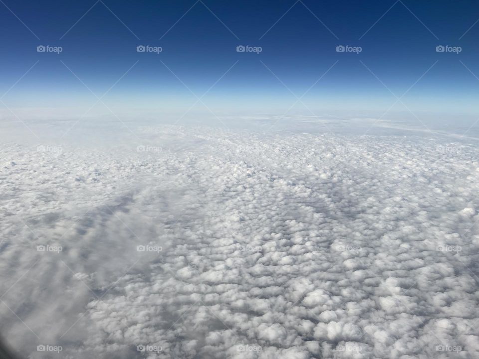 Above the clouds against a tranquil, gradient blue sky