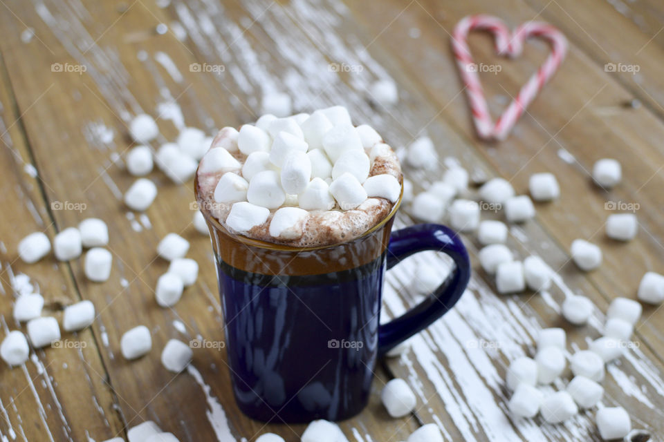 A mug of hot chocolate topped with marshmallows and peppermint on a cold winter night