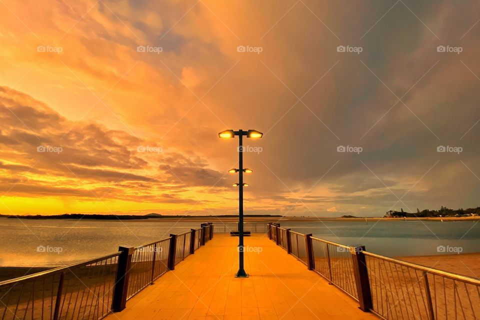 Orange sunset, street light in the middle of the pier