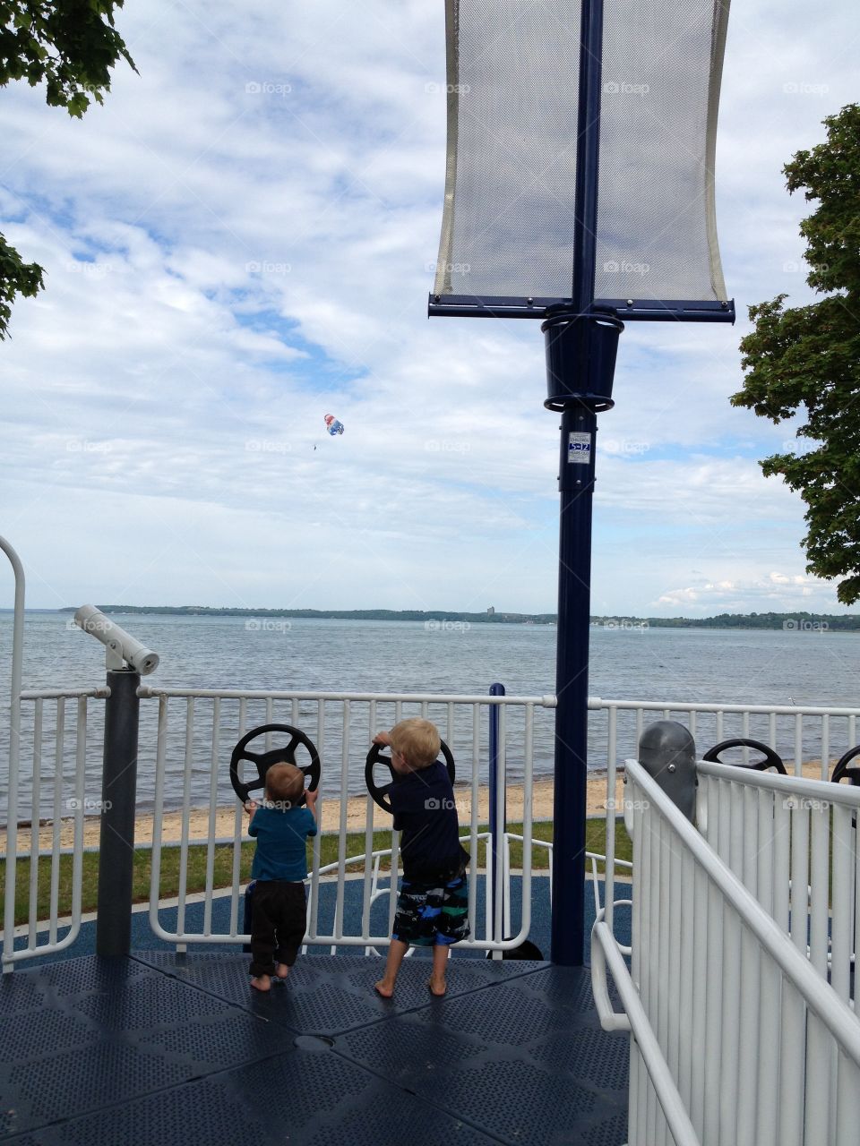 Bayside playground boys. 2 young boys playing on boat play structure overlooking Grand Traverse Bay
