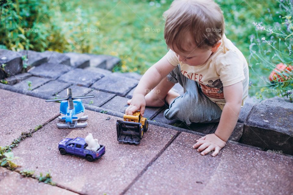 little boy playing with cars on the street