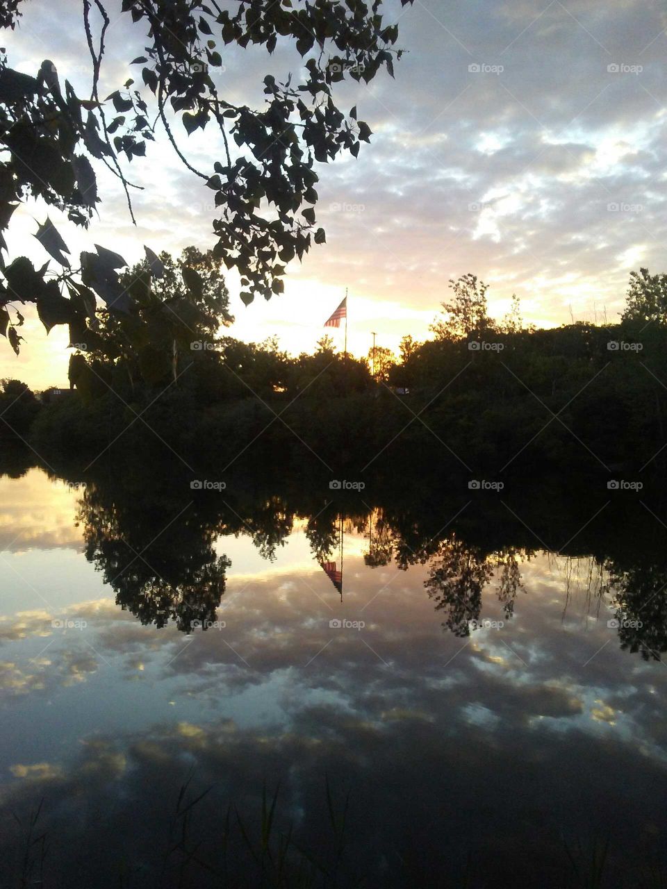 American Flag at Sunrise with Reflection in Pond