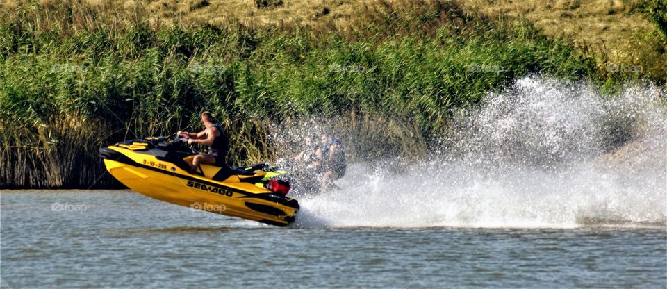 yellow jetski racing over the water with a white cloud of waterdrops behind it