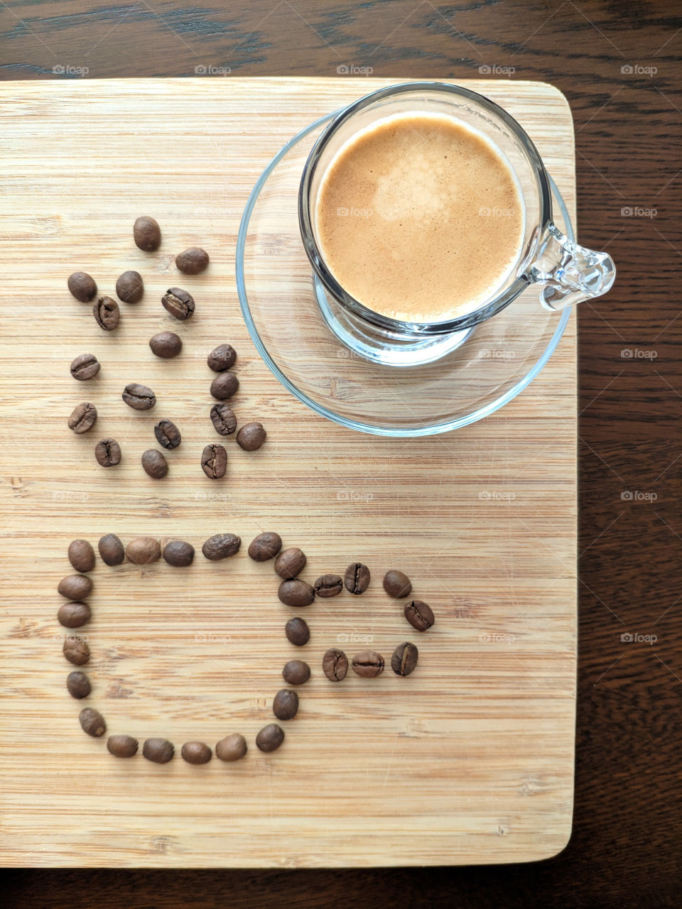 An espresso coffee served in a cup and a drawing of a cup made with coffee beans
