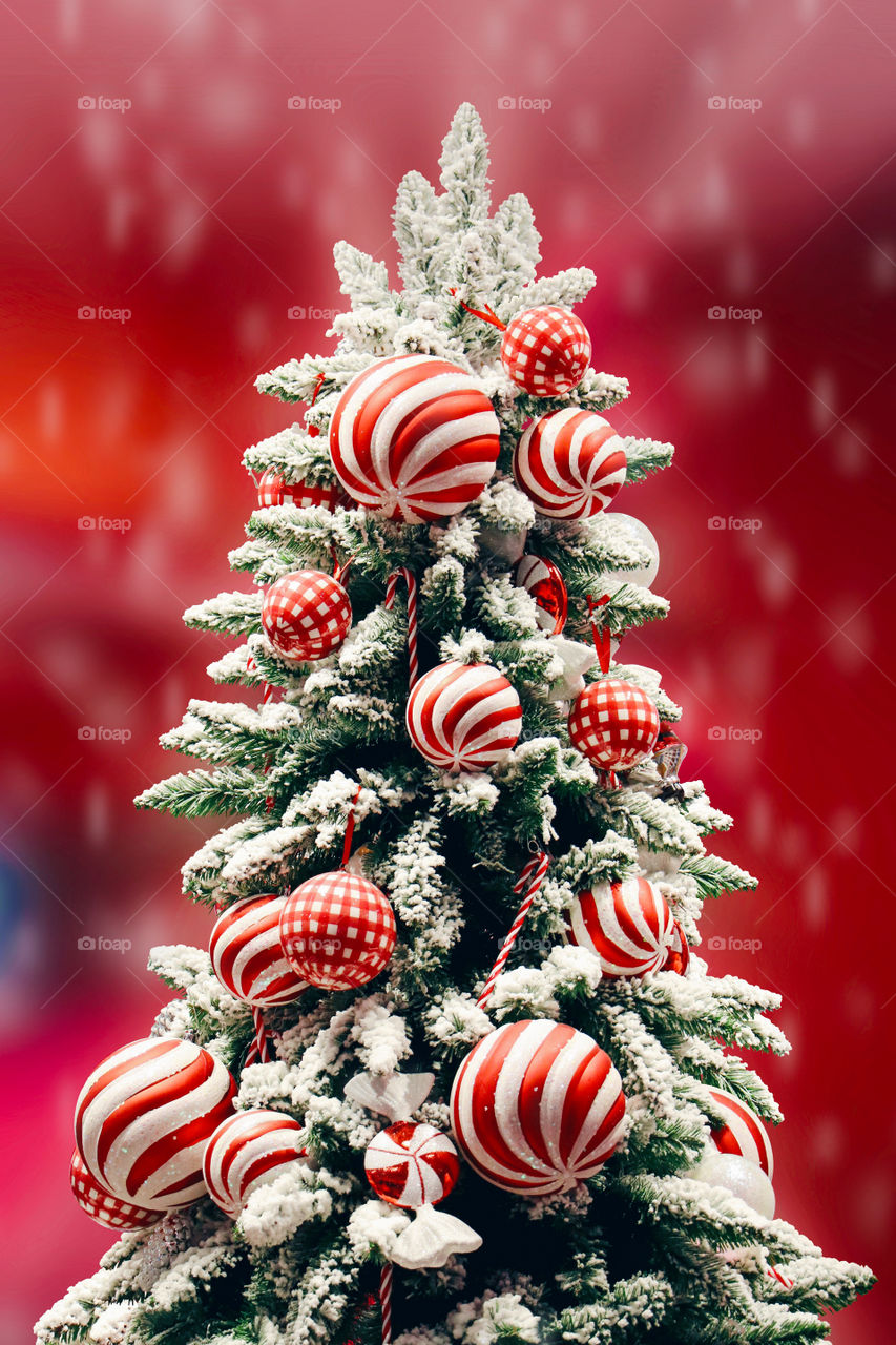 Decorated beautiful Christmas tree on winter snow with red gradient background 