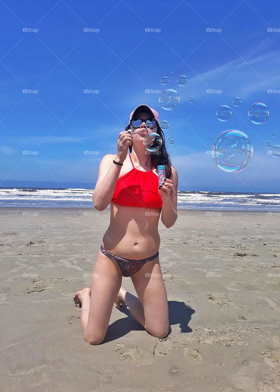 Girl on beach vacation blowing soap bubbles