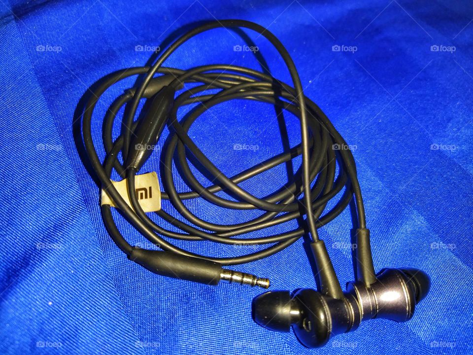 Xiaomi basic wired earphones black  against a blue background