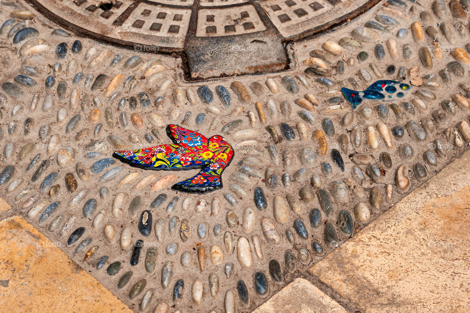 Decorative bird tile in pavement.