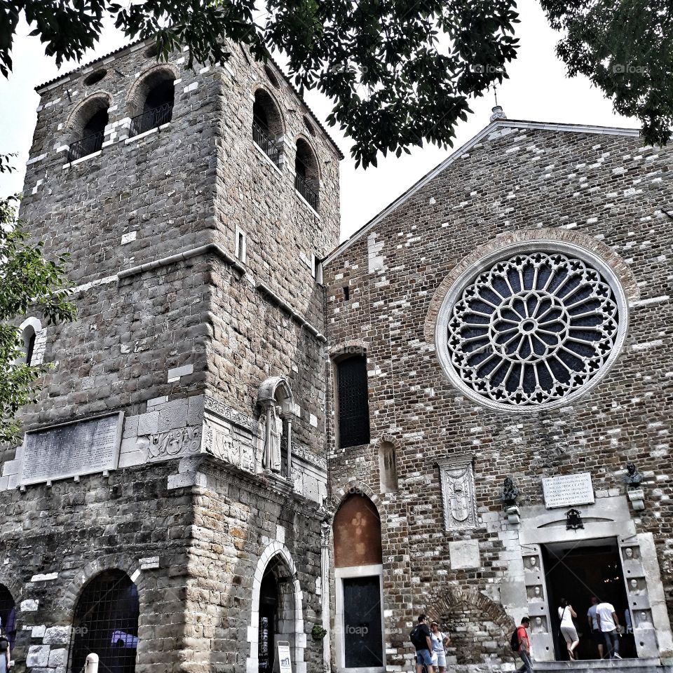 Basilica in the Italian city of Triest. The photo shows a rosette with a tower of stone.
