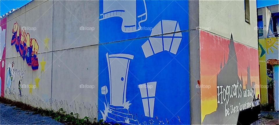 A colorful facade predominately painted in an intense indigo blue faces us as part of one of a house in the „Munich“ „Olympic Village“. It was here during the 1972 games that several „Israeli“ athletes were killed. 2022. Hypnotic Productions