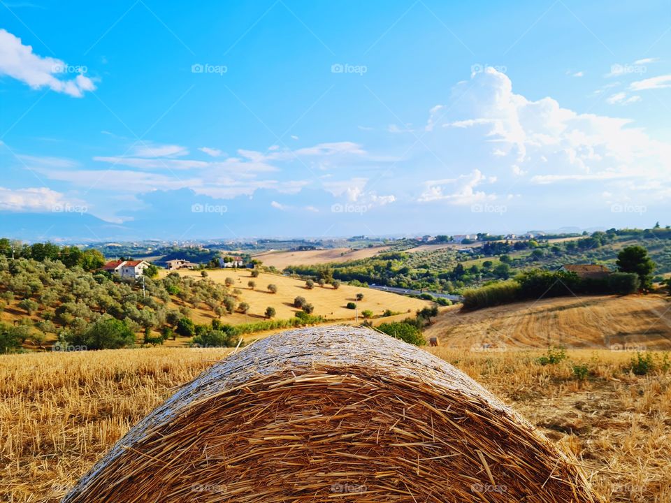 Italian summer landscape with harvested fields and round bales in the foreground
