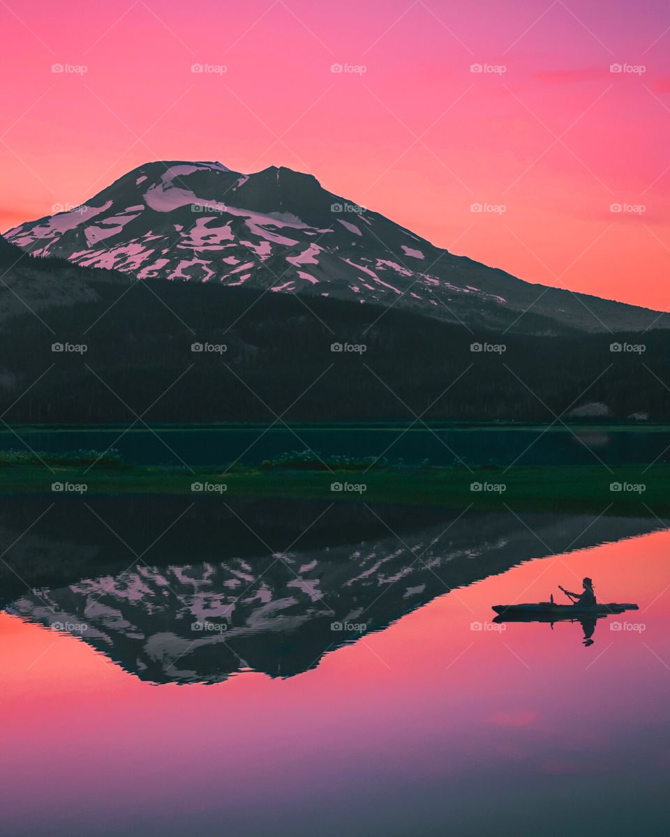 Kayaker and mountain during tranquil summer sunset on Sparks Lake, Oregon