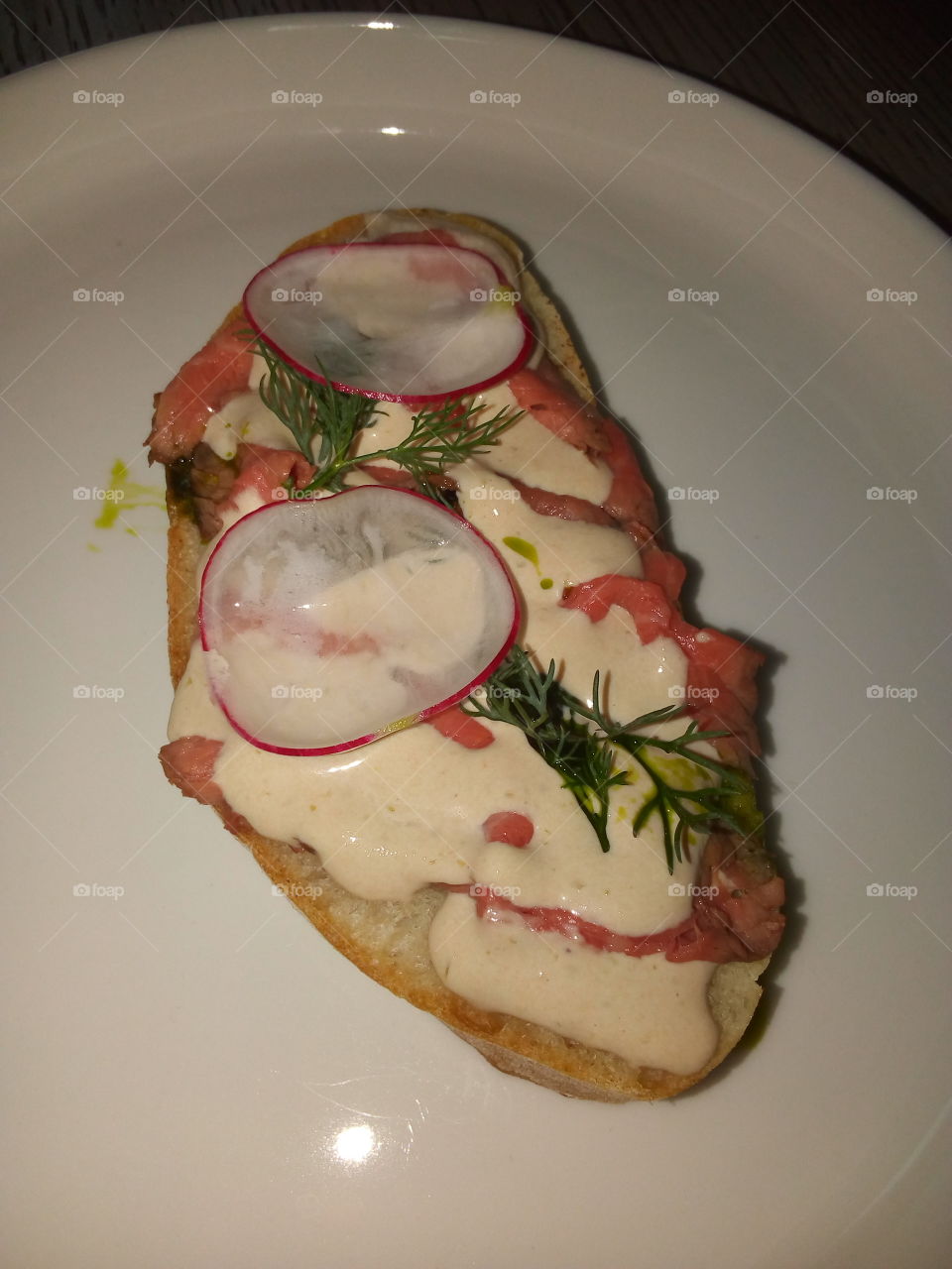 Sandwich with meat, sauce, herbs.