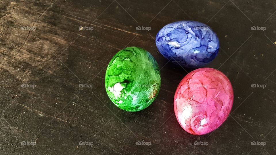Three colorful Easter Eggs on a wooden table