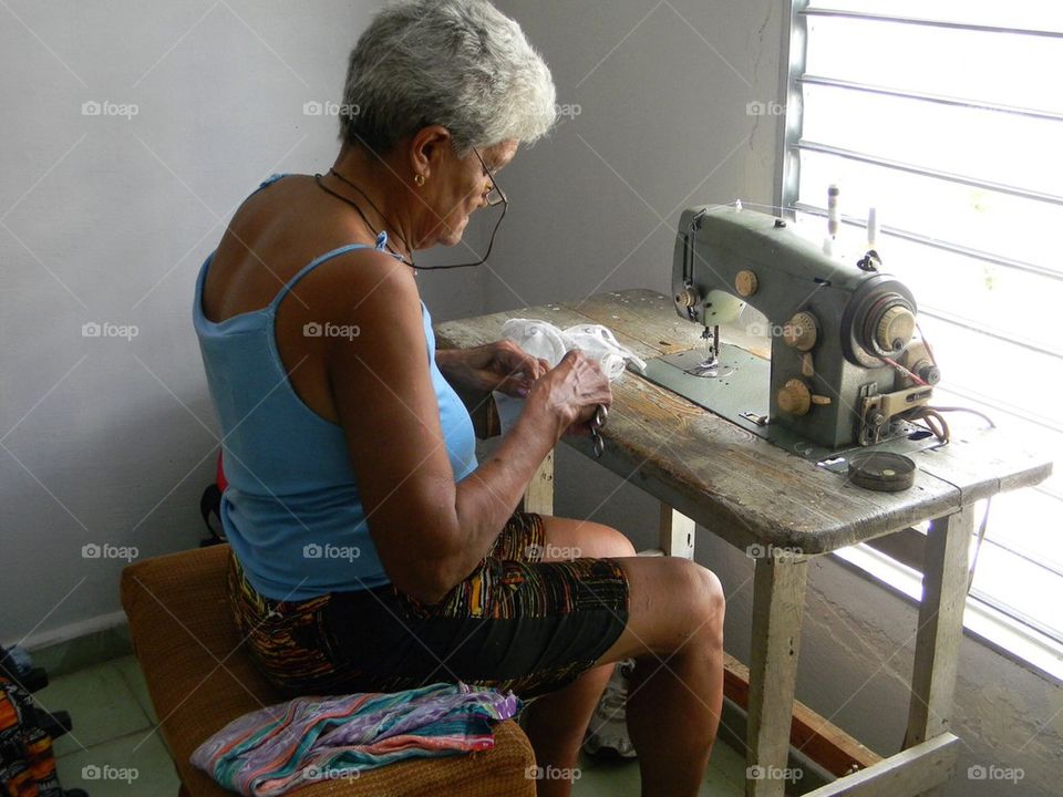 Mending my business . Lady in Cuba using an antique sewing to mend clothing in her neighborhood to make money. She is a hard working lady




