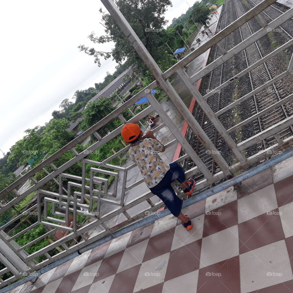 A littile boy injoying the view train track from over bridge