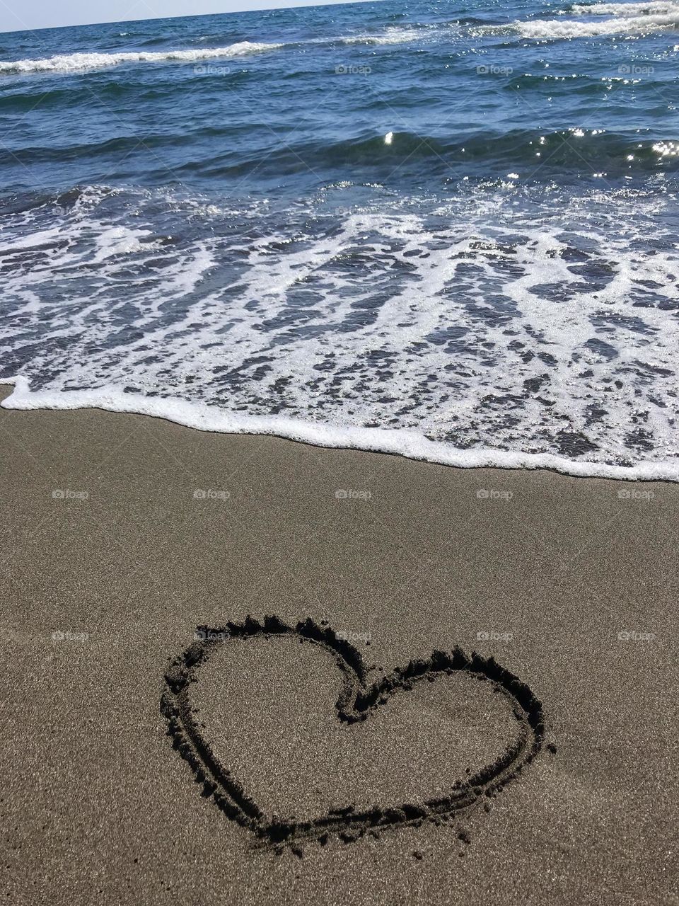 Sea waves and hearts in the sand