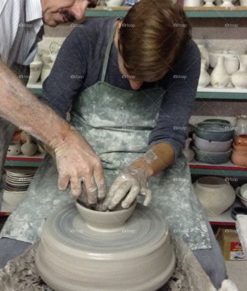 Learning how to throw a clay pot on a wheel.